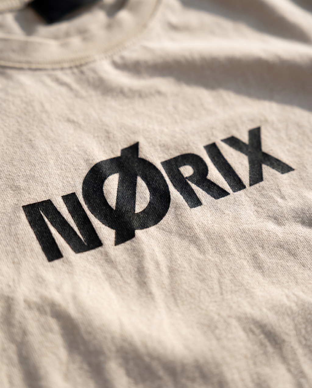 Close-up of NØRIX NORIX logo print on Concrete Sand oversized t-shirt, 230 GSM premium cotton